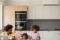 Das Bild zeigt einen jungen Vater mit seinen beiden Töchtern in der Küche, an der Wand befindet sich eine Carrier Klimaanlage.